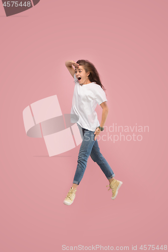 Image of Freedom in moving. Pretty young woman jumping against pink background