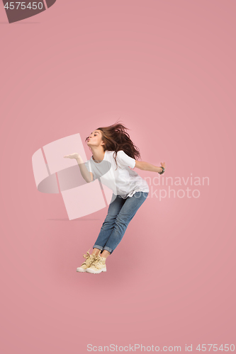 Image of Freedom in moving. Pretty young woman jumping against pink background