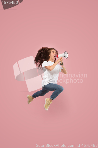 Image of Beautiful young woman jumping with megaphone isolated over pink background