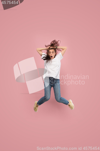 Image of Freedom in moving. Pretty young woman jumping against pink background