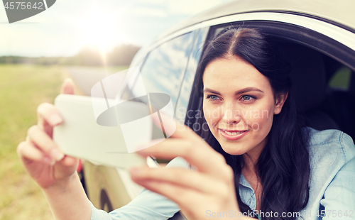 Image of happy young woman driving in car with smartphone