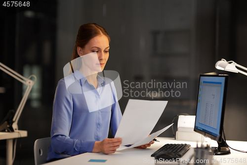 Image of businesswoman with papers working at night office
