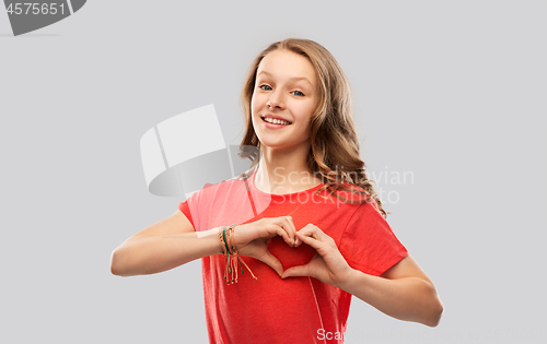 Image of smiling teenage girl in red making hand heart