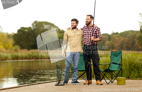 Image of friends with fishing rods and net at lake or river