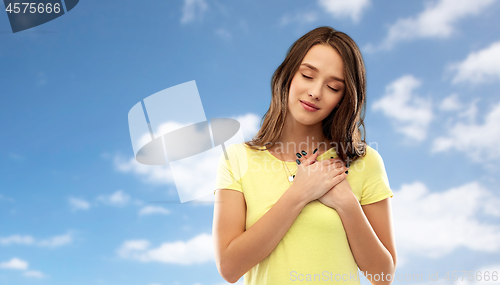 Image of smiling teenage girl holding hands on heart