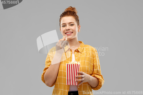 Image of smiling red haired teenage girl eating popcorn
