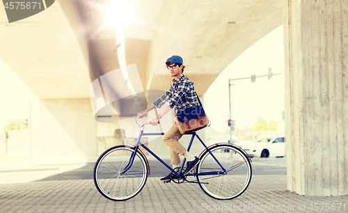 Image of young hipster man with bag riding fixed gear bike