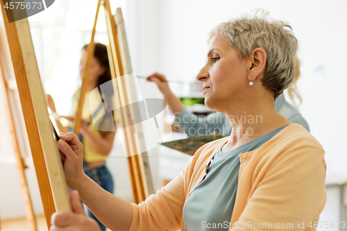 Image of senior woman drawing on easel at art school studio