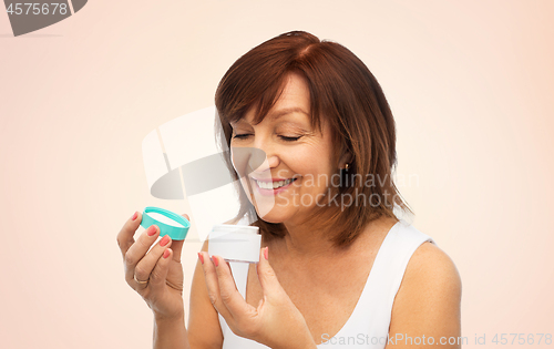 Image of smiling senior woman with cream jar