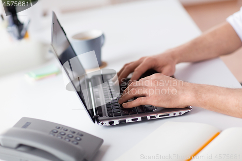 Image of hands typing on laptop computer at office