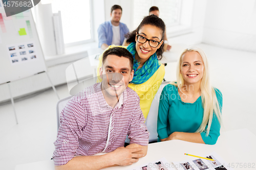 Image of creative team with photos at model agency office