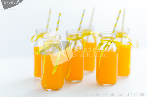 Image of orange juice in glass bottles with paper straws