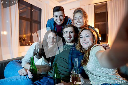 Image of happy friends taking selfie at home party