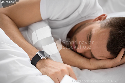 Image of close up of man with smart watch sleeping in bed