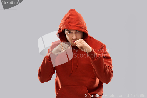 Image of man in red hoodie fighting with fists or boxing