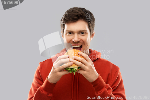 Image of happy young man eating hamburger
