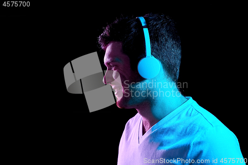 Image of man in headphones over neon lights of night club