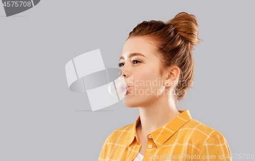 Image of red haired teenage girl blowing bubble gum