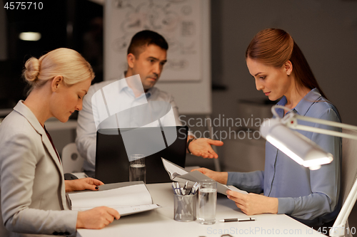 Image of business team with laptop working at night office