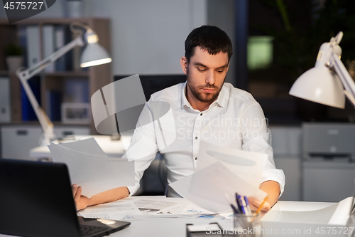 Image of businessman with papers working at night office