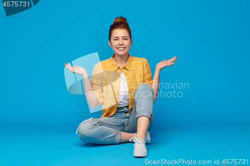 Image of smiling red haired teenage girl shrugging