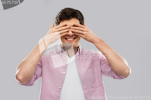 Image of man closing his eyes by hands over grey background