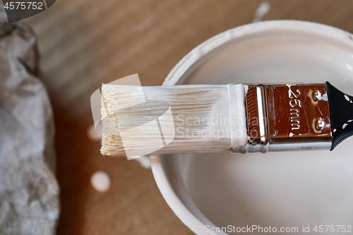 Image of Paint brush on a can of white wall paint