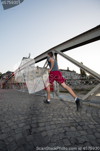 Image of man jogging across the bridge at sunny morning