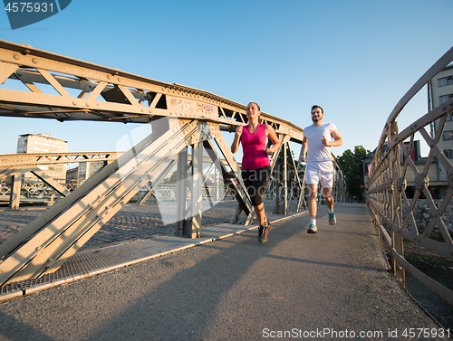 Image of young couple jogging across the bridge in the city