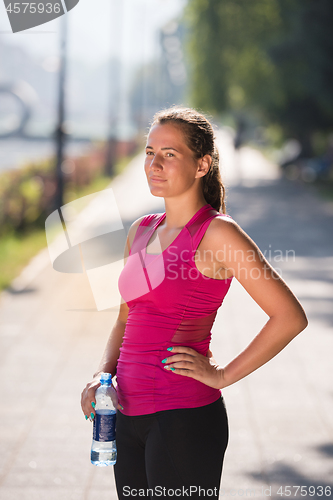 Image of woman drinking water from a bottle after jogging