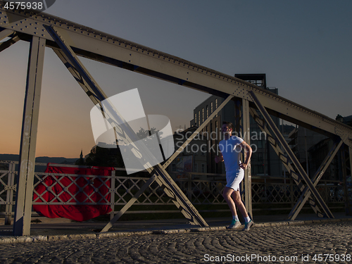 Image of man jogging across the bridge in the city