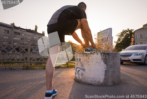 Image of man tying running shoes laces