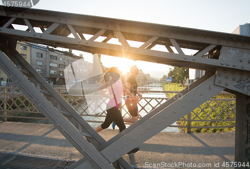 Image of young couple jogging across the bridge in the city