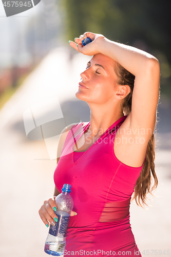 Image of woman drinking water from a bottle after jogging