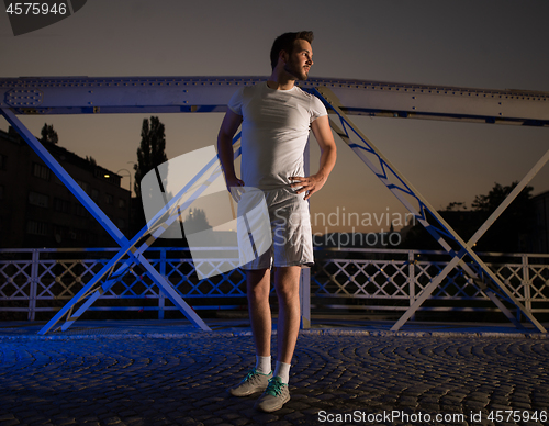 Image of man jogging across the bridge in the city