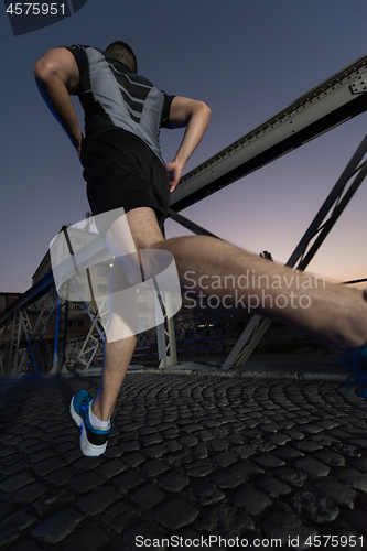 Image of man jogging across the bridge in the city