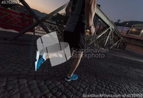 Image of man jogging across the bridge in the city