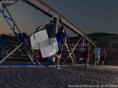 Image of young people jogging across the bridge