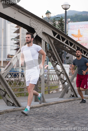 Image of group of young people jogging across the bridge