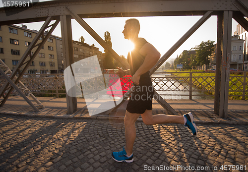 Image of man jogging across the bridge at sunny morning