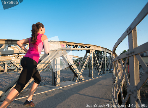 Image of woman jogging across the bridge at sunny morning