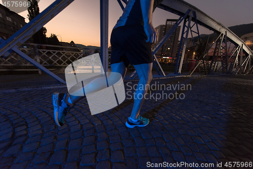 Image of man jogging across the bridge in the city