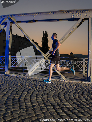 Image of man jogging across the bridge in the city