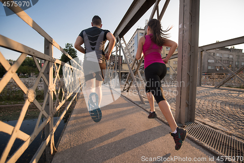 Image of young couple jogging across the bridge in the city