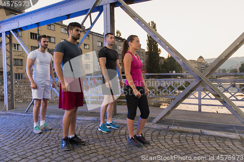 Image of group of young people jogging across the bridge