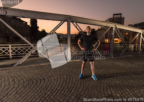 Image of man jogging across the bridge in the city