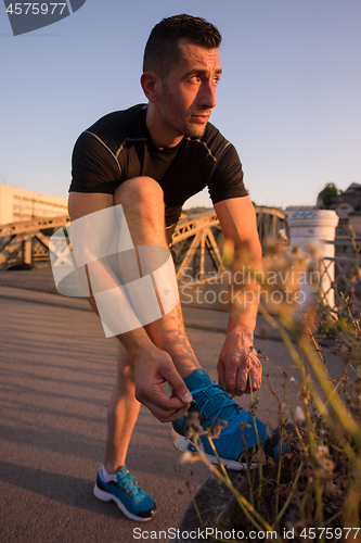 Image of man tying running shoes laces