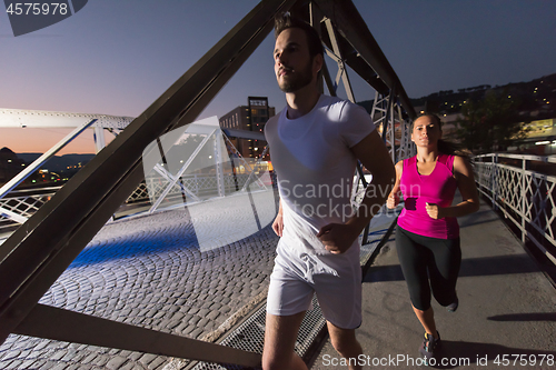 Image of couple jogging across the bridge in the city