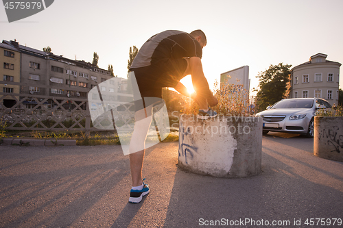 Image of man tying running shoes laces