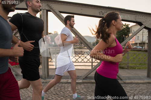 Image of group of young people jogging across the bridge